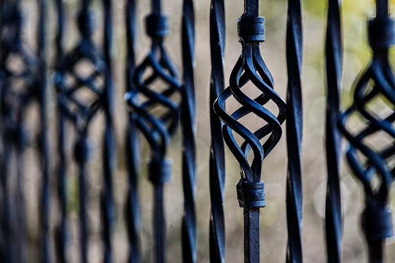 A wrought iron fence with decorative spiral flourishes on every third bar photographed with shallow depth of field, combining structure and elegance to represent the thoughtful and self-determined nature of personal boundaries in the Assertive Boundaries and Communication Campaign at Availia.
