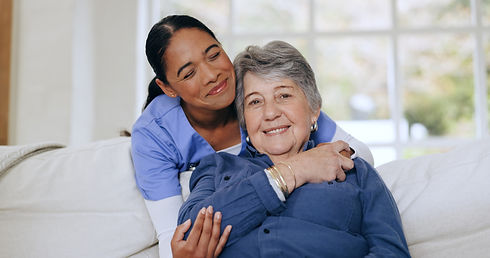senior-woman-nurse-hug-sofa-retirement-home-caregiver-support-smiling-love-friendly-empath