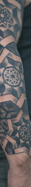 Ornamental tattoo with patterns on the mans arm, tattoo is black and gray has pattern and mandala