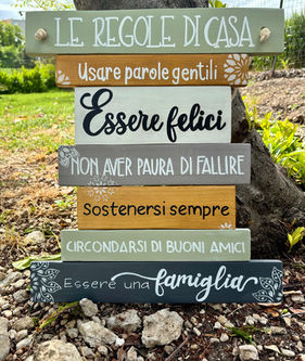Targa decorativa in legno riciclato, dipinta a mano con frasi positive sulle Regole di Casa. Colori vivaci, stile rustico e Artigianale, ideale per arredare ingressi, salotti e spazi esterni. Un pezzo unico che porta calore, gentilezza e atmosfera famigliare.