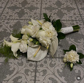 Elegant white bridal bouquet featuring calla lilies, roses and carnations with fresh green foliage, accompanied by a matching white floral buttonhole.