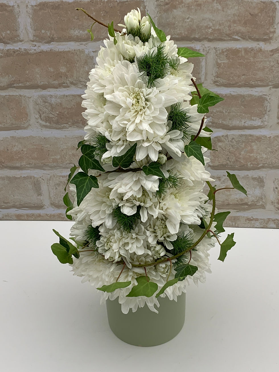 Joy flower arrangement with white chrysanthemums, ivy and delicate greenery in a matte ceramic pot.