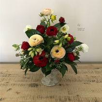 Floral arrangement with cream and red ranunculuses, greenery and delicate filler flowers in a ceramic vase