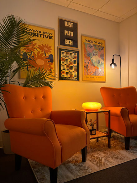 Cozy waiting area at Novaluna Mental Health featuring a warm yellow lamp, modern flip clock, and calming decor designed to help clients feel safe and welcome.