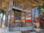 Ancient bronze temple bell hanging in a wooden belfry at Chuson-ji temple Hiraizumi Japan with blazing red autumn maples visible behind