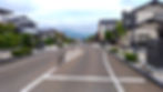 Wide empty street in Hiraizumi Japan with tidy traditional houses on both sides and mountains in the background