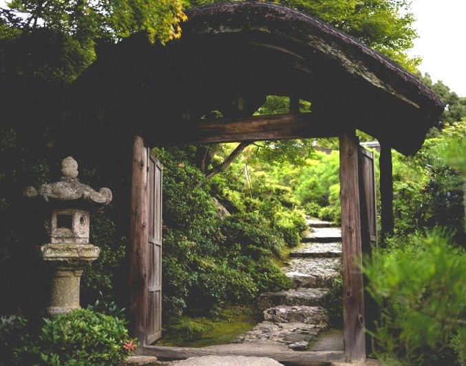 Thatched gate framed by moss and foliage at Ōkōchi Sansō in Kyoto’s Arashiyama district