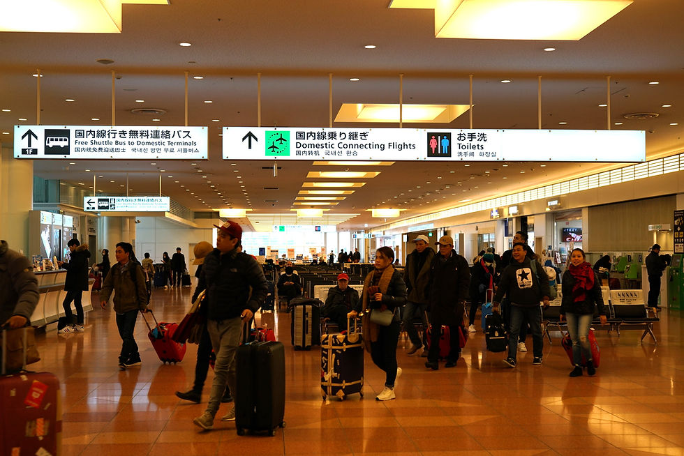 Travelers walking through Haneda Airport arrival terminal in Tokyo Japan with Japanese directional signage overhead