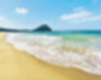 Soft waves and golden sand at Kikugahama Beach in Hagi, with forested hills in the distance.