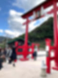 Visitors trying to throw coins into a high offertory box atop a torii gate at Motonosumi Inari Shrine.