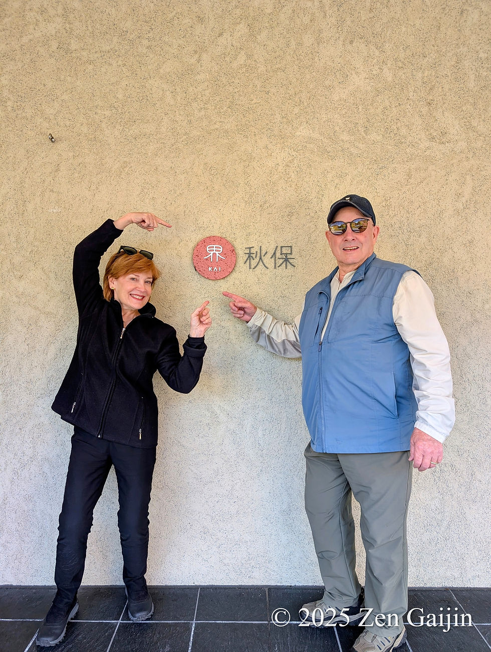 Two travelers standing beside the KAI Akiu ryokan sign in Miyagi Prefecture
