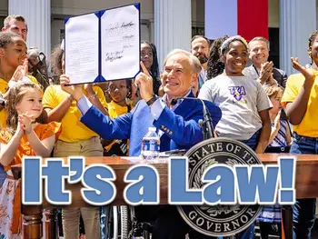 Governor Abbot holding up a signed bill with smiling children around him