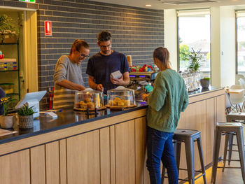 two people behind coffee shop counter with person ordering