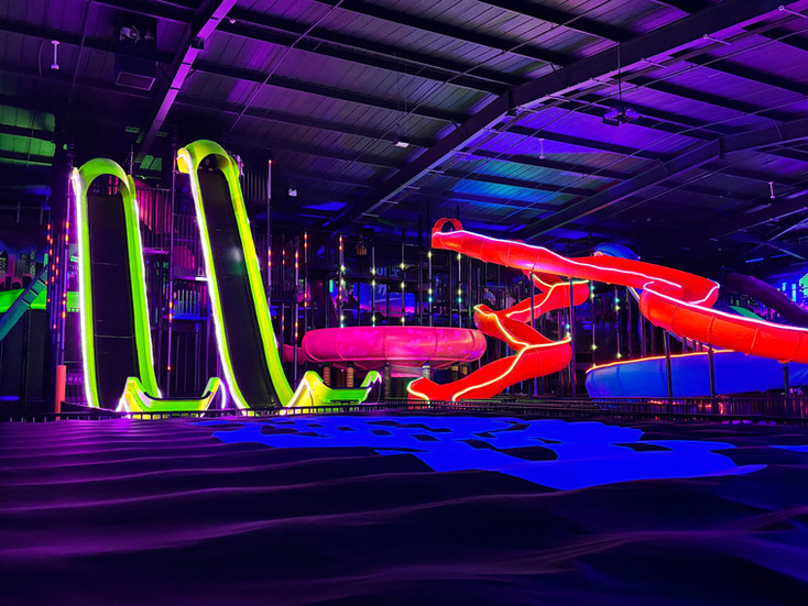 Two indoor slides in adventure park with disco ball hanging from ceiling