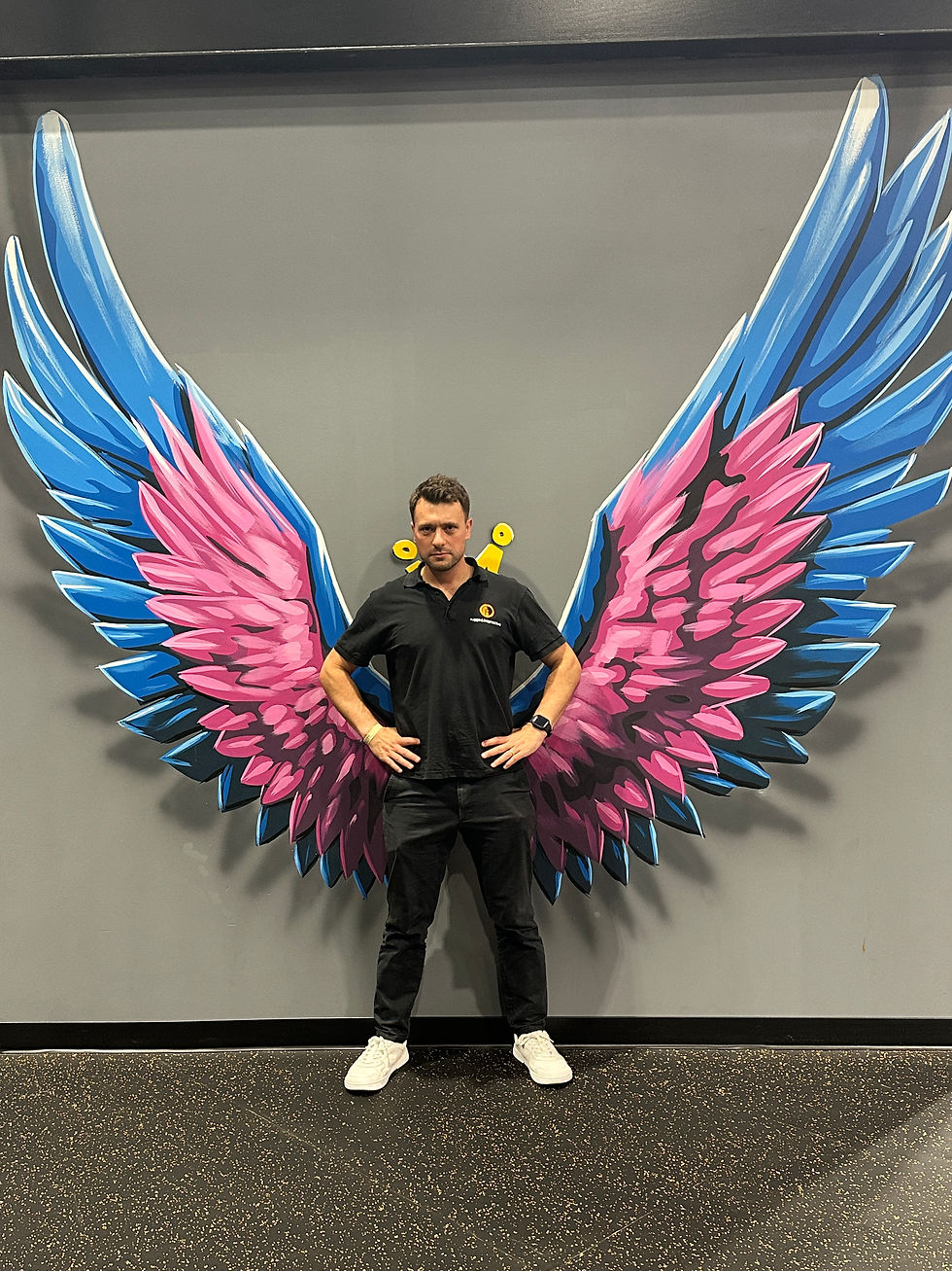 Robin Mills stood with hands on hips infront of wing mural