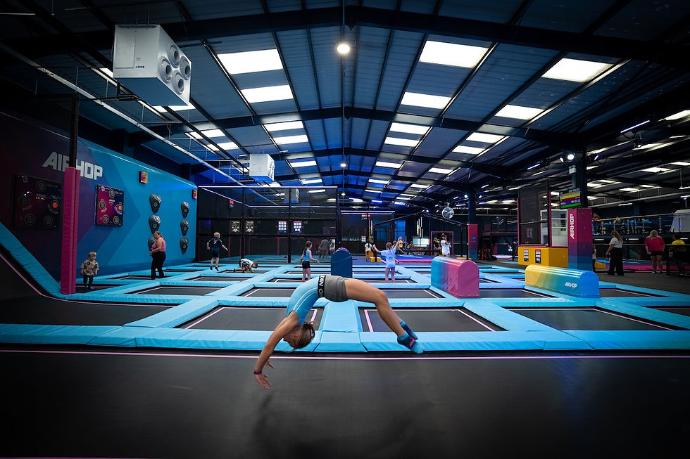 Girl in leotard doing back flip on trampoline bed in large trampoline park