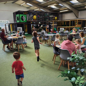 Boy running towards soft play in indoor playground now with AI generated people filling the cafe