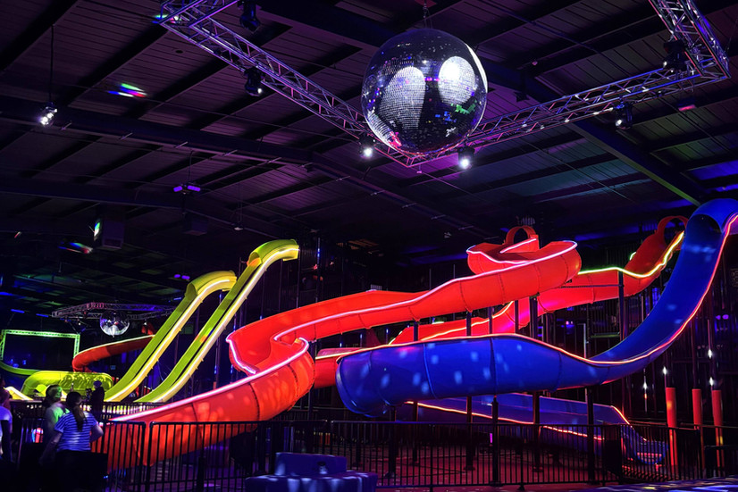 Three indoor slides in adventure park with disco ball hanging from ceiling