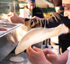 Pizzaiolo tossing dough at the wood-fired oven
