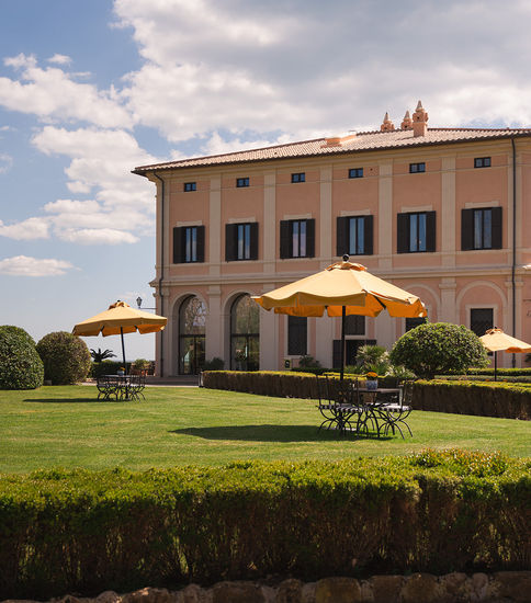 The villa and its garden seen from the lawn under parasols