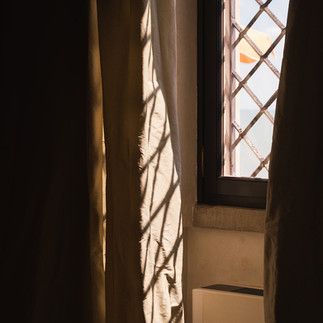 View through window curtains at a historic Italian villa by the sea