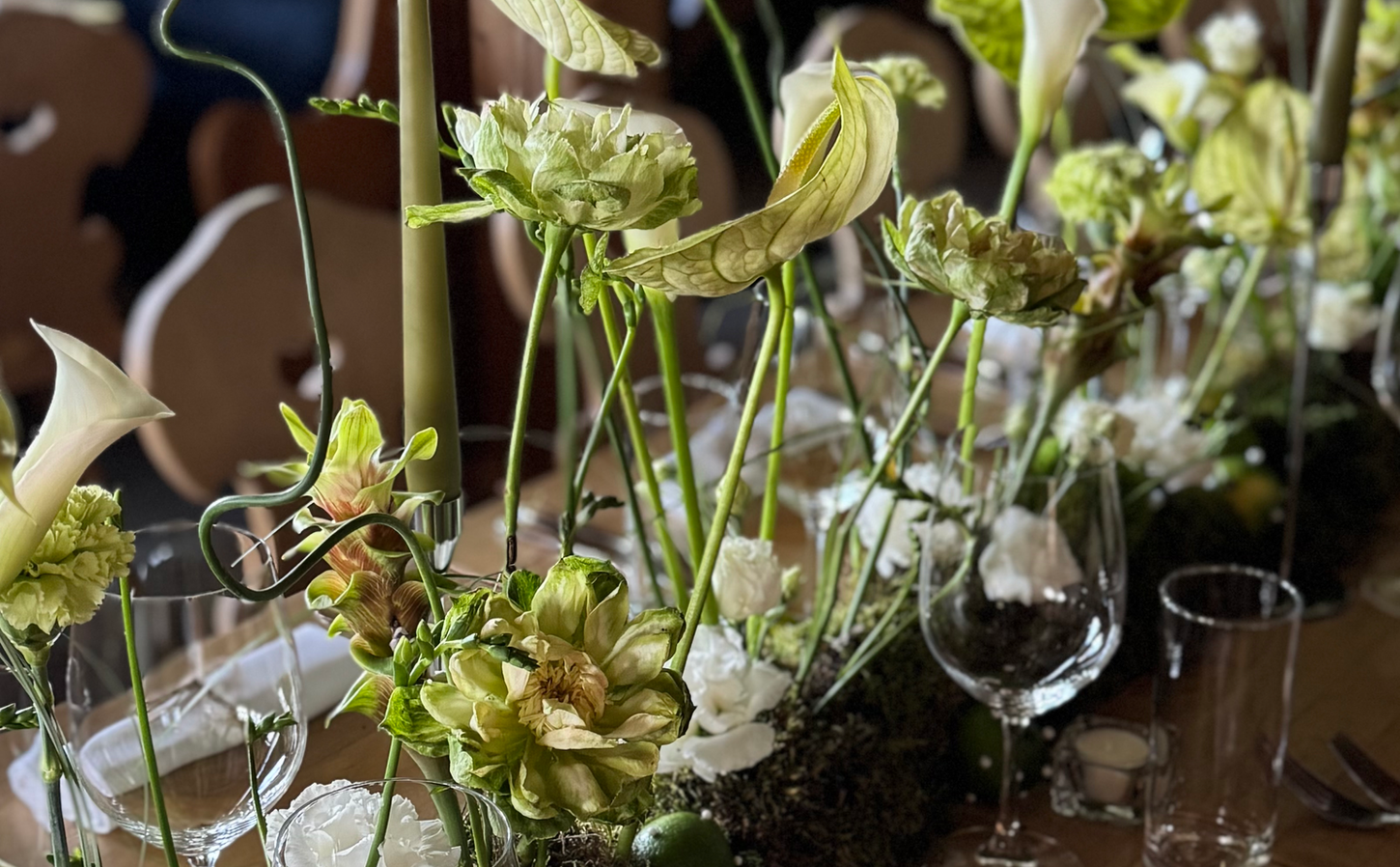 Low arrangement of anthurium, moss and white flowers beside the glassware