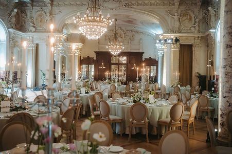 The ballroom set for dinner beneath chandeliers and painted ceilings