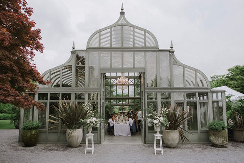 Wedding reception at Enea Orangerie in Rapperswil, with elegant floral decorations at the entrance and inside the glasshouse.