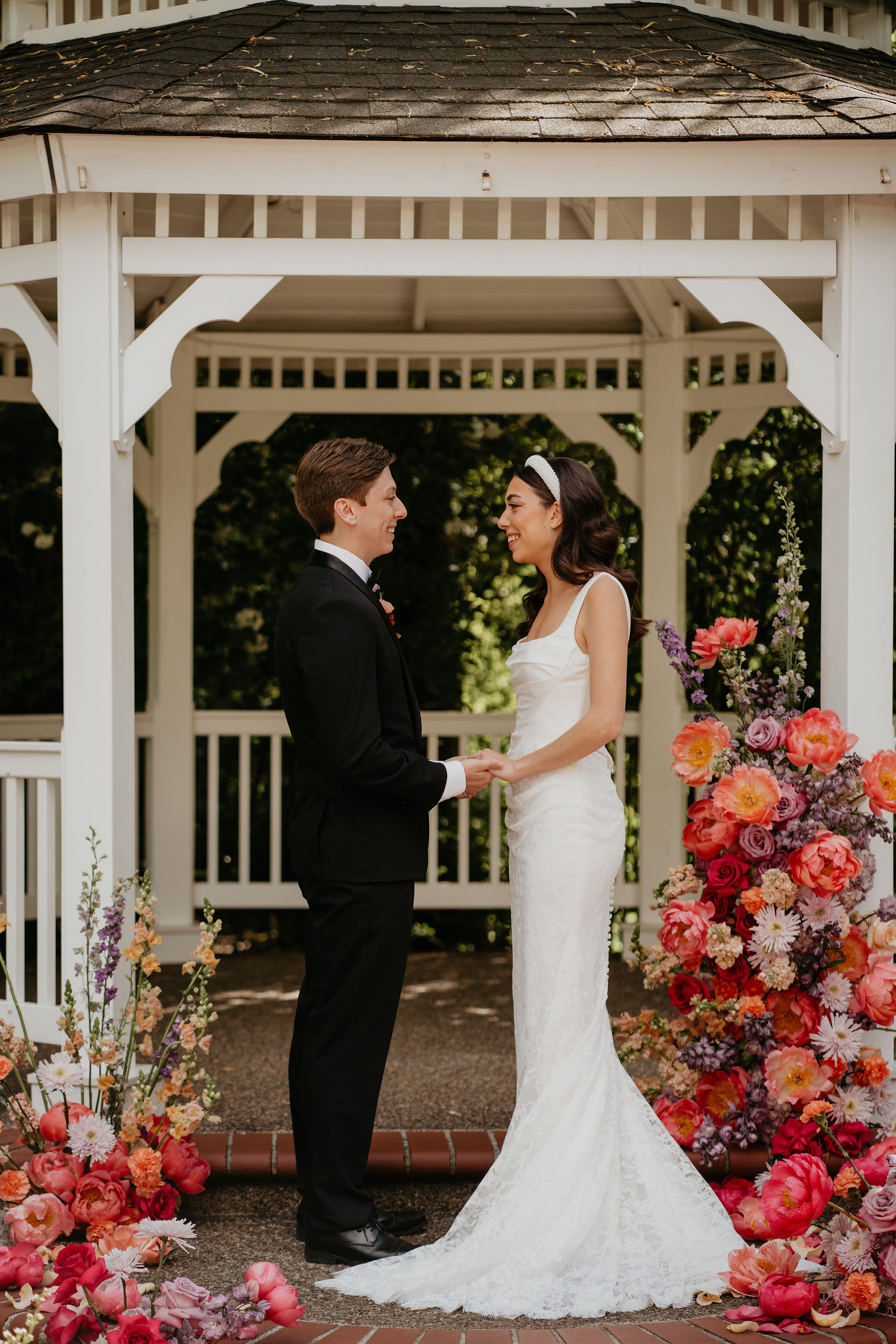 Bride and groom stand amidst their bright wedding flowers in Abigail's Garden.