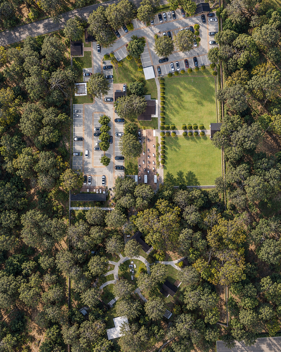 Vista aérea conceptual de Evergreen con jardín de eventos, áreas de estacionamiento, senderos y cabañas entre árboles.