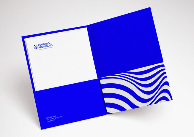 Pasta de documentos aberta com design interno em azul vibrante. O lado direito apresenta o padrão de ondas brancas e azuis, e o lado esquerdo contém papéis timbrados com o logotipo no topo, demonstrando a papelaria corporativa completa.