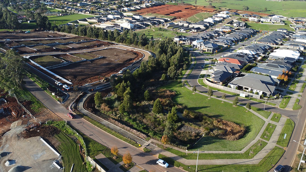 Aerial view of finished homes and parkland at Ferntree Ridge, with earthworks for the next stage behind