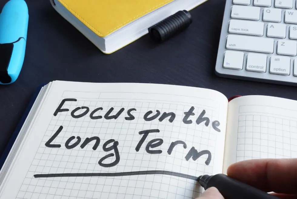 The statement 'Focus on the Long-term' written on a notebook