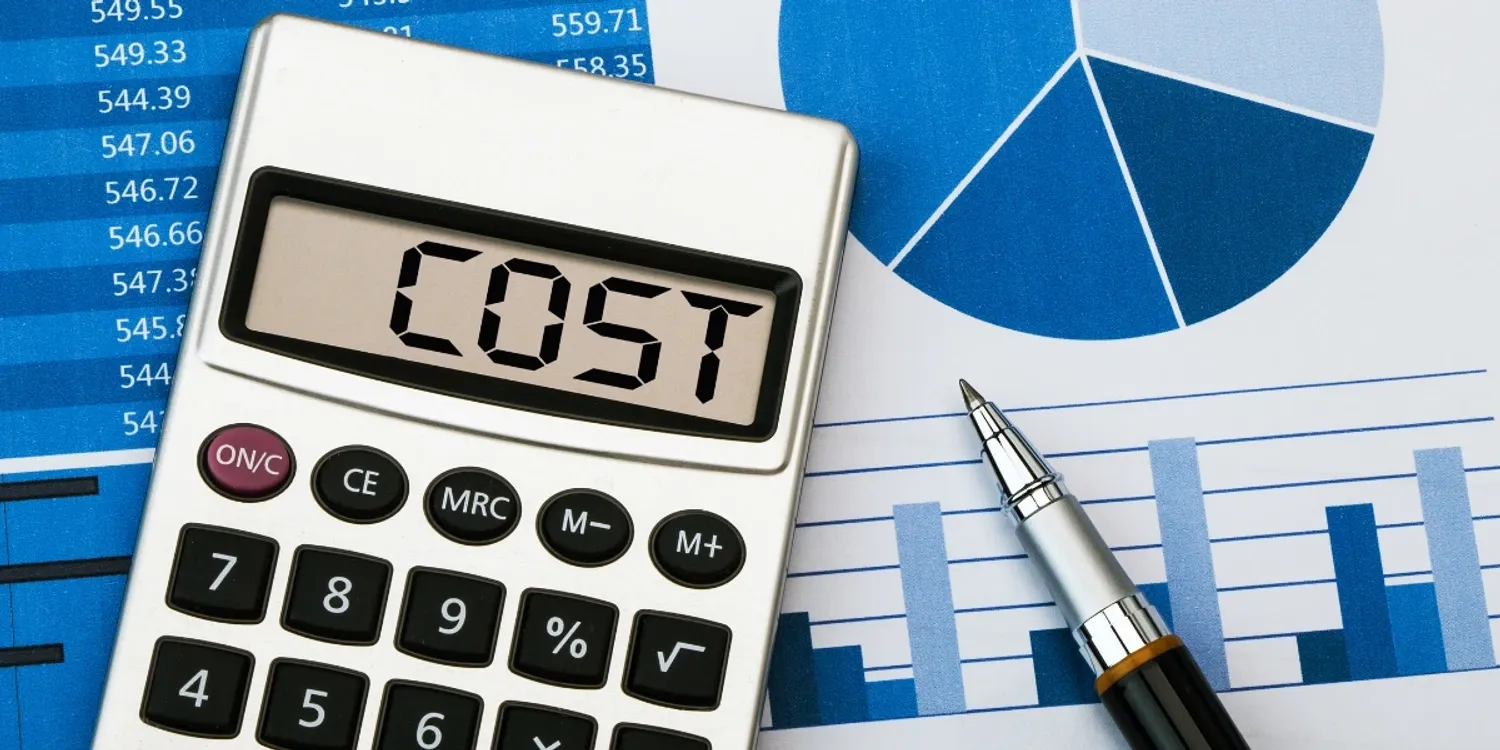A calculator with the word "Cost" displayed on the screen. Pie charts and numbers in the background