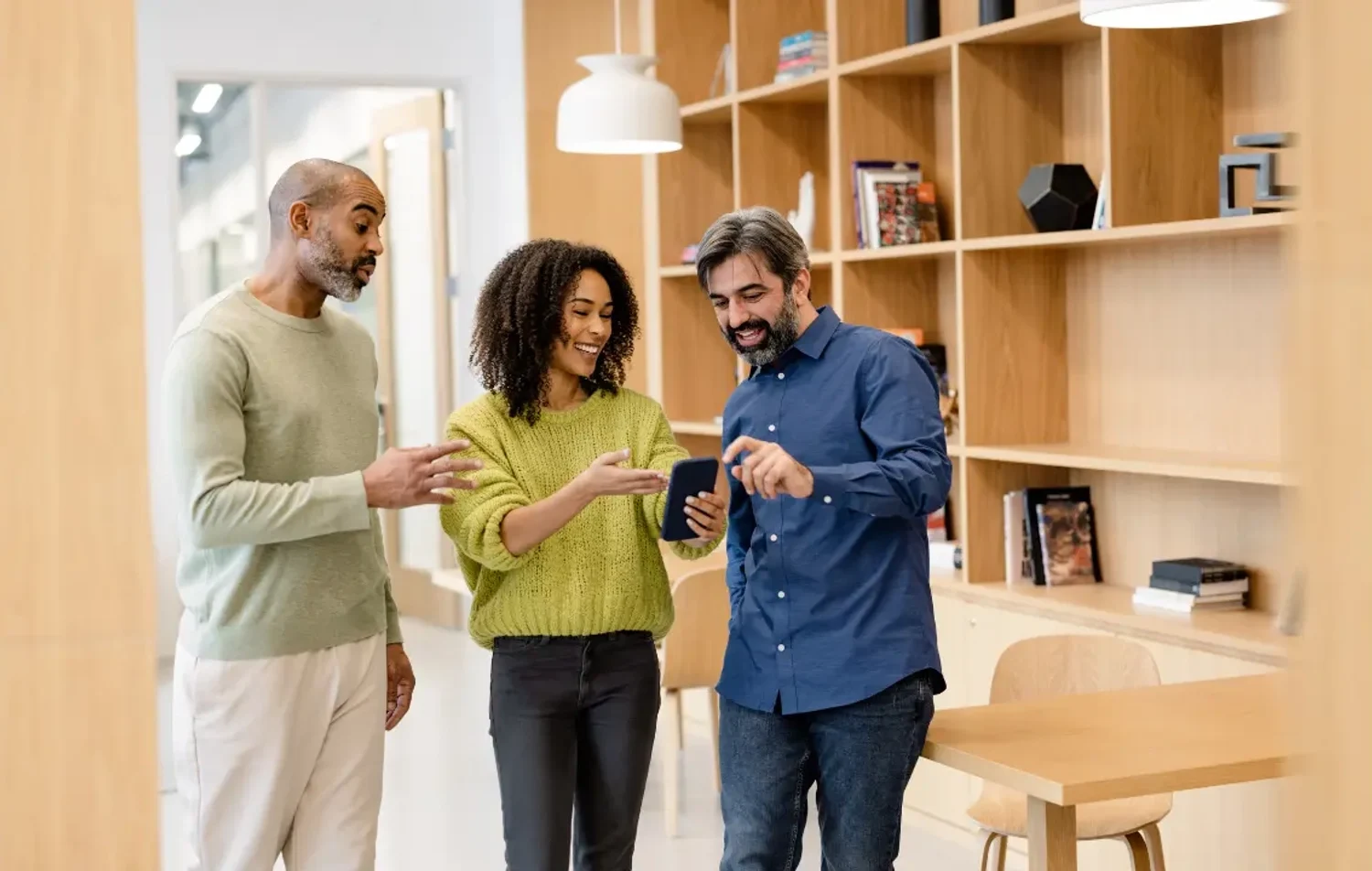 Three people talking about something they see on a mobile device.