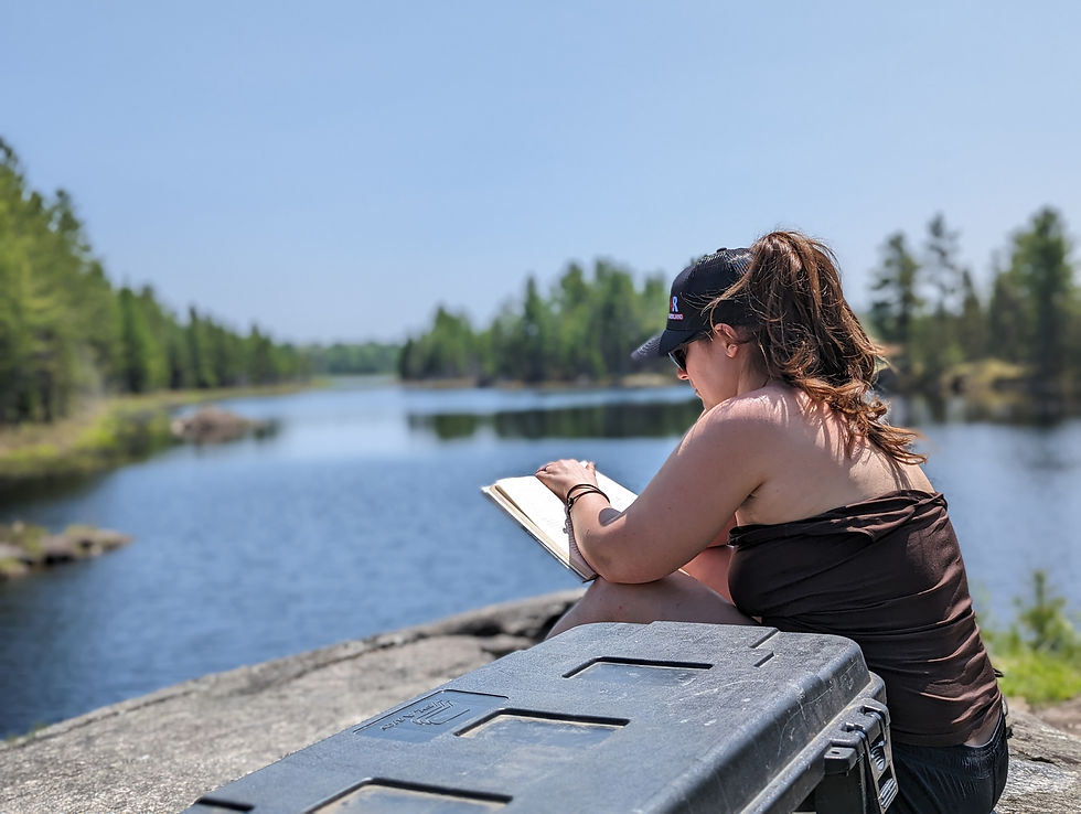 A women taking in a little reading time beside a lake.