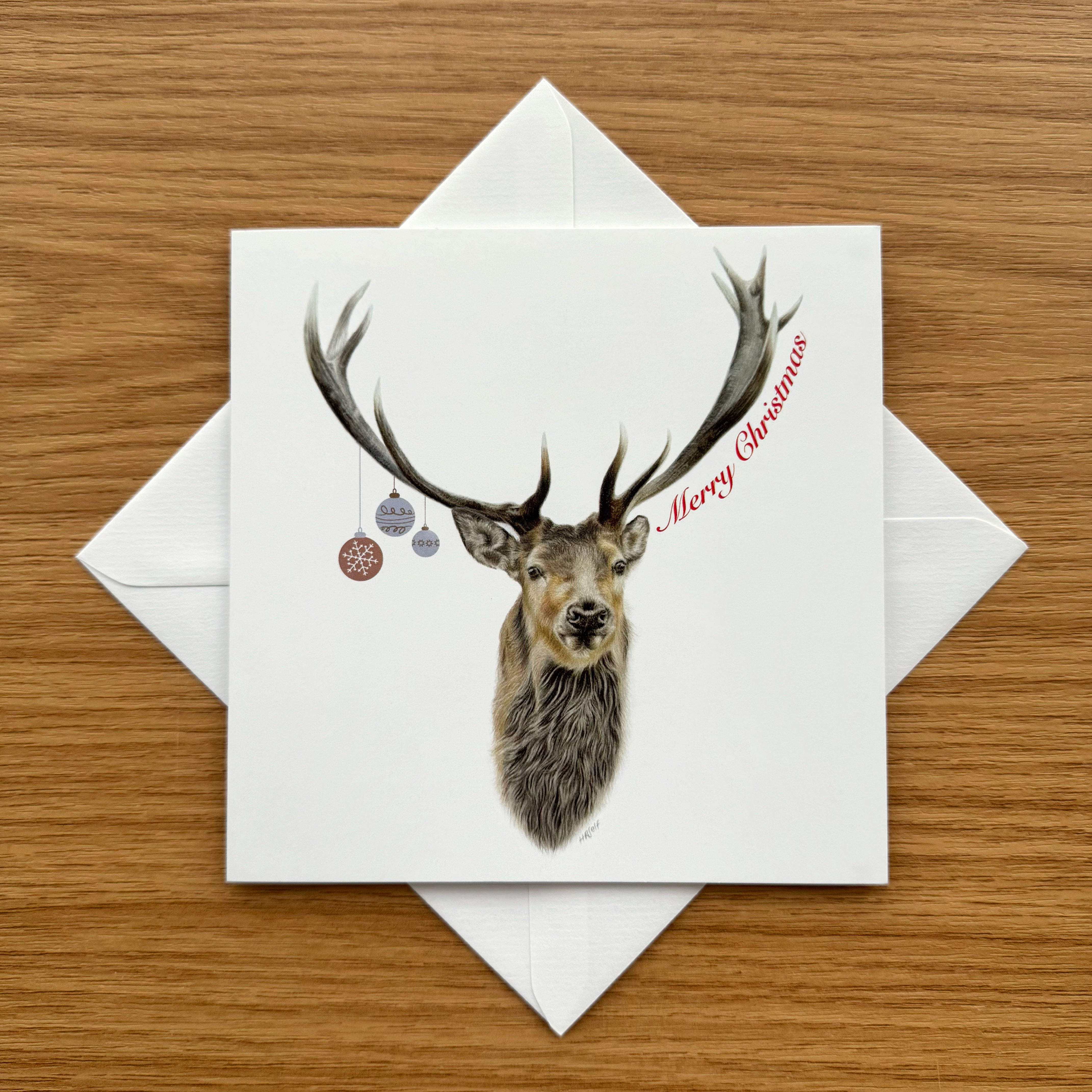 A matt Christmas card of a Stag's head with 'Merry Christmas' wording, with a white envelope displayed