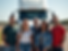 A group of diverse employees standing together in front of a Pro Haul Systems truck, smili