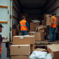 Three workers loading boxes in a truck, wearing orange vests, on the road.