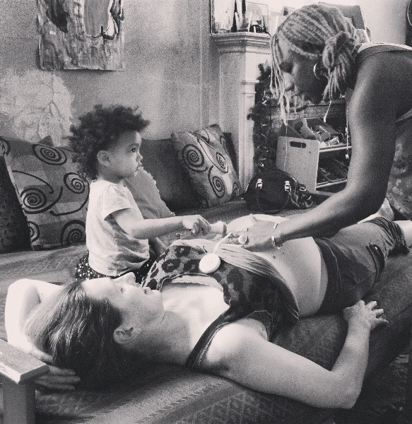 A home birth Midwife offering care while including the help of a toddler child.