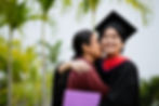 mother-embracing-woman-wearing-graduation-gown-against-sky.jpg