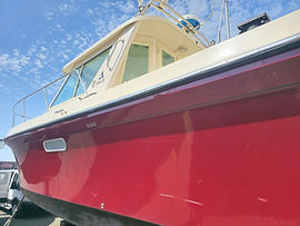 Glossy red hull on an Albin 31 cabin cruiser, up on stands in a Bellingham boatyard