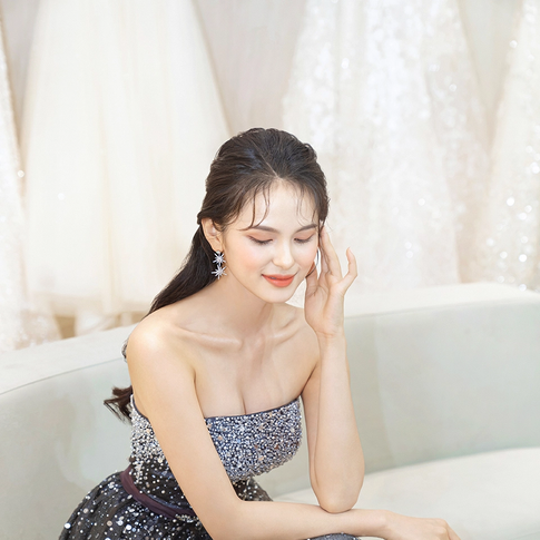 váy cưới đen đính đá - cô dâu tạo dáng ngồi đưa tay lên tai - phong cách Hàn Quốc