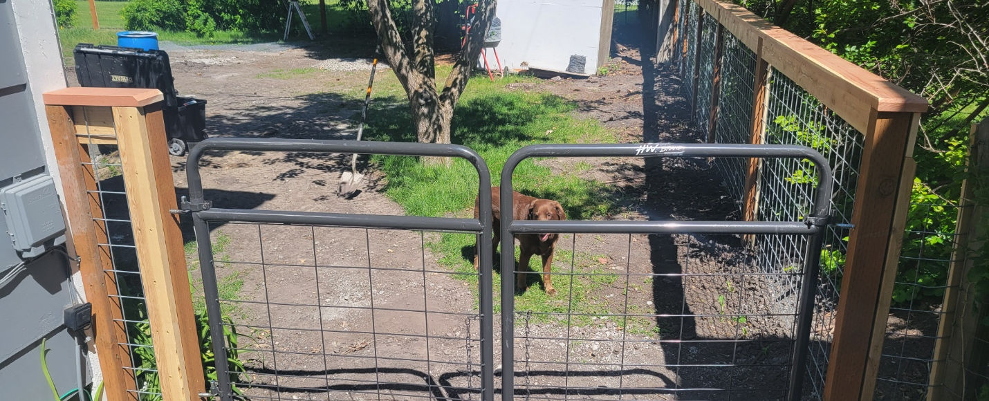 Wood fence with hog wire panels and a metal gate installed in Bozeman Montana