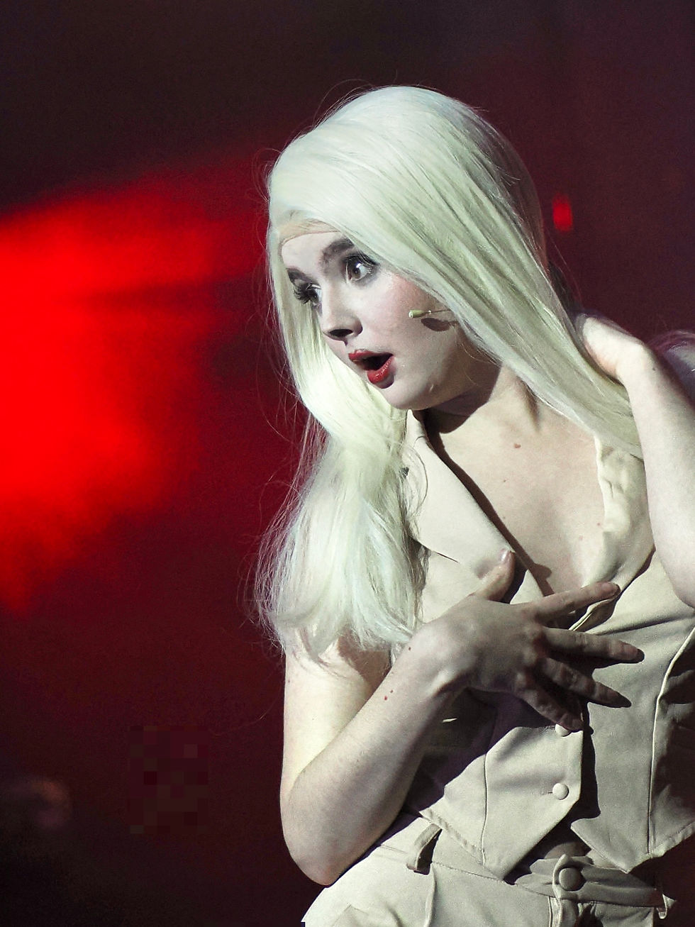 Blonde person with shocked expression under red light
