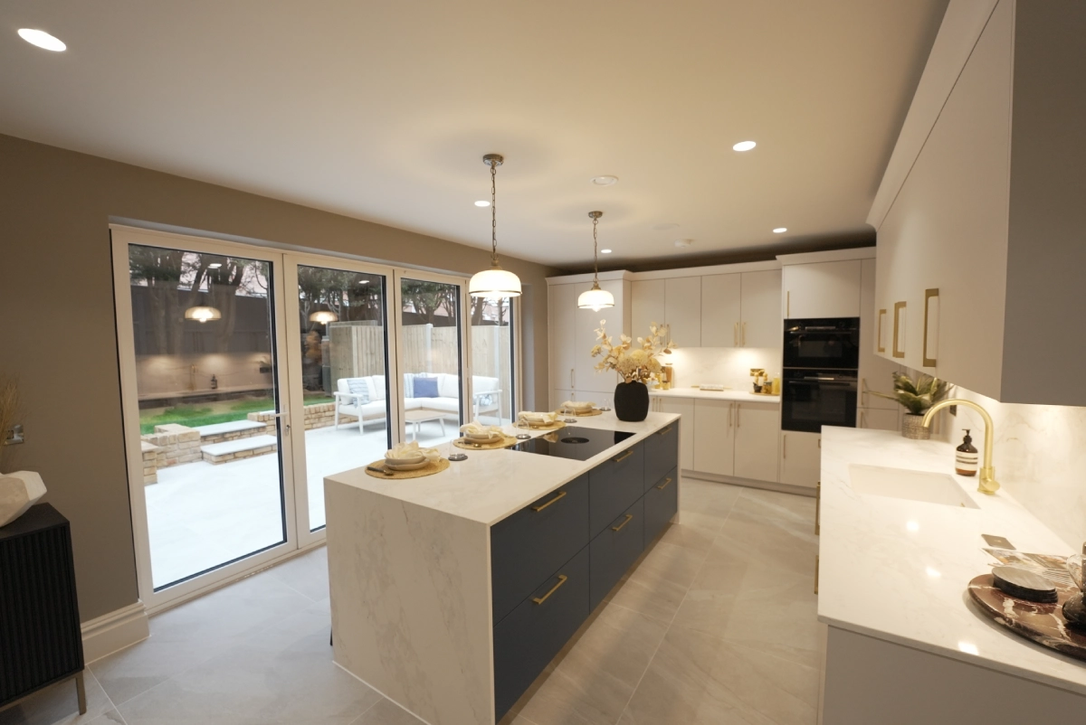 Modern kitchen with elegant lighting, featuring a white marble island, navy cabinets, and glass doors opening to a patio. Cozy and inviting atmosphere.