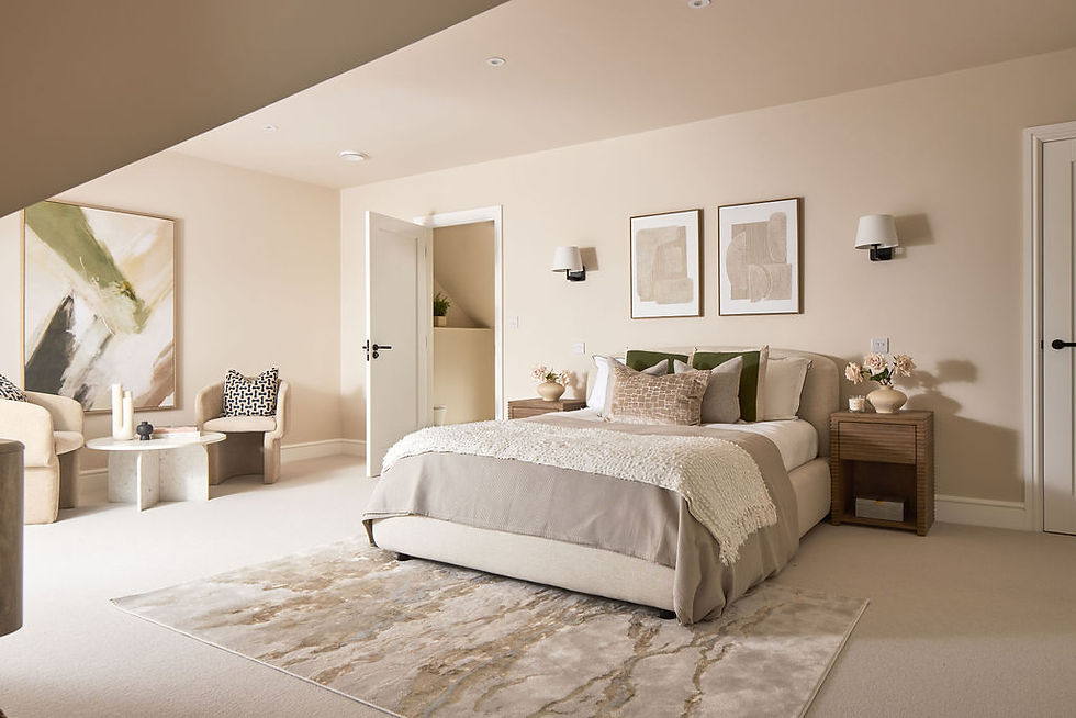 Beige bedroom with a neatly made bed, abstract art, armchairs, and a small table. Soft lighting creates a calm, cozy atmosphere.