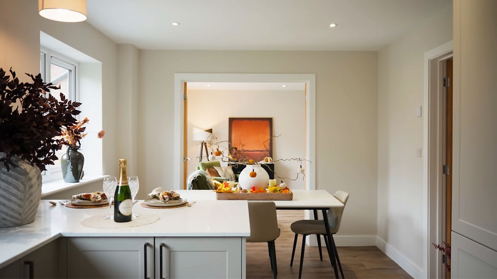 A cozy dining area with a white table, autumn decor, champagne, and place settings. Relaxing room view with armchair and orange artwork.