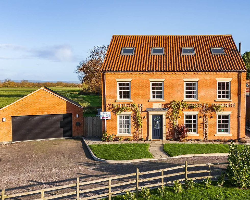 Brick house with orange roof in countryside, large windows, and a “Win Me” sign. Green lawn, clear sky, and peaceful rural setting.