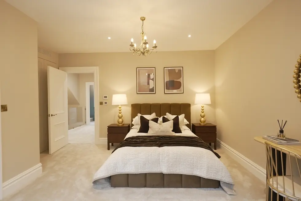 Elegant bedroom with a plush bed, cushions, and two lamps on nightstands. Beige walls, chandelier, and abstract art create a cozy ambiance.